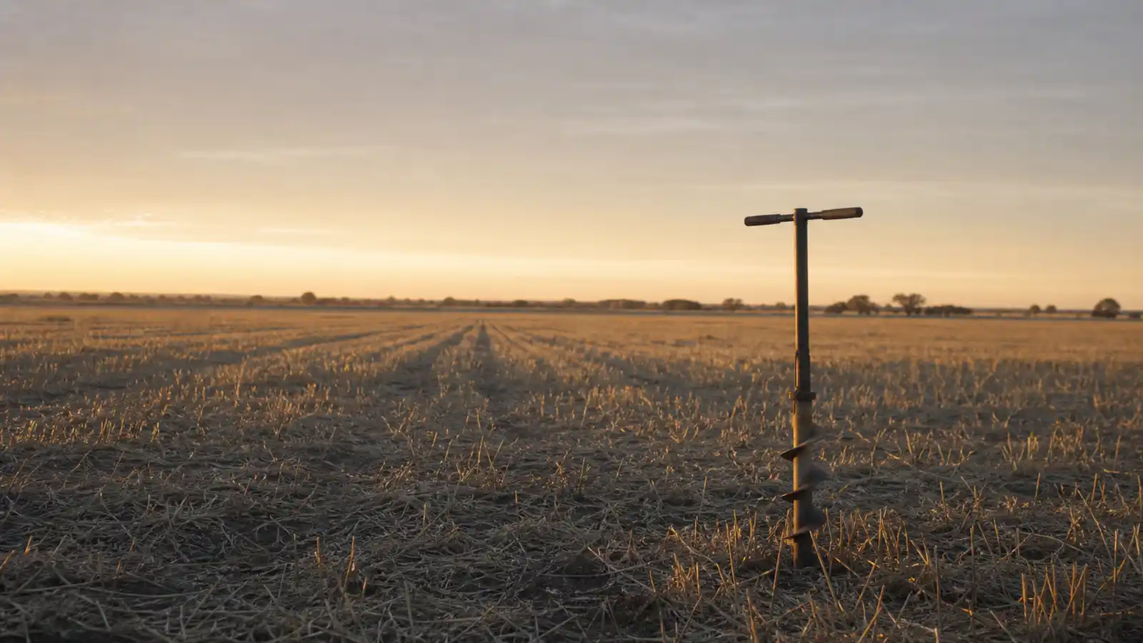 Soil auger standing in a grain paddock at dawn, agronomist professional indemnity insurance
