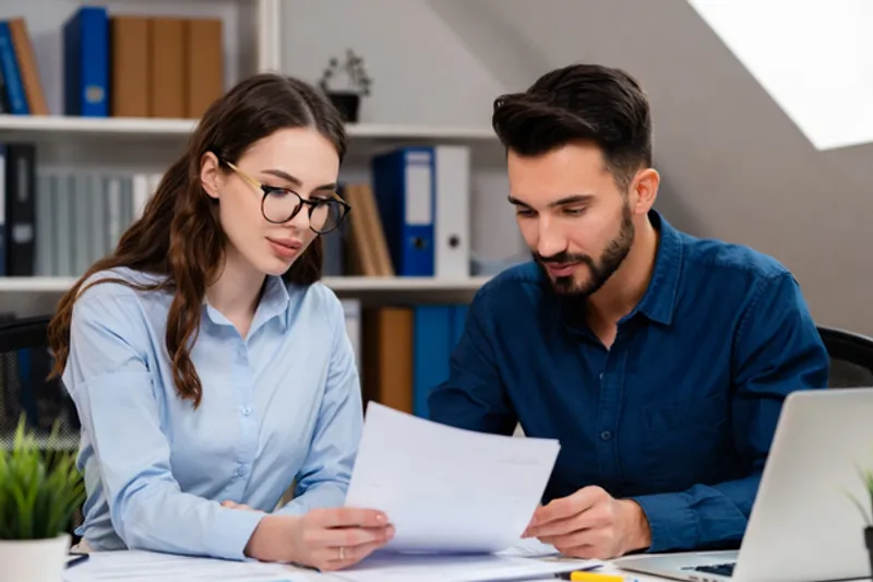 Two insurance brokers reviewing a premium funding agreement with a client in a modern office.