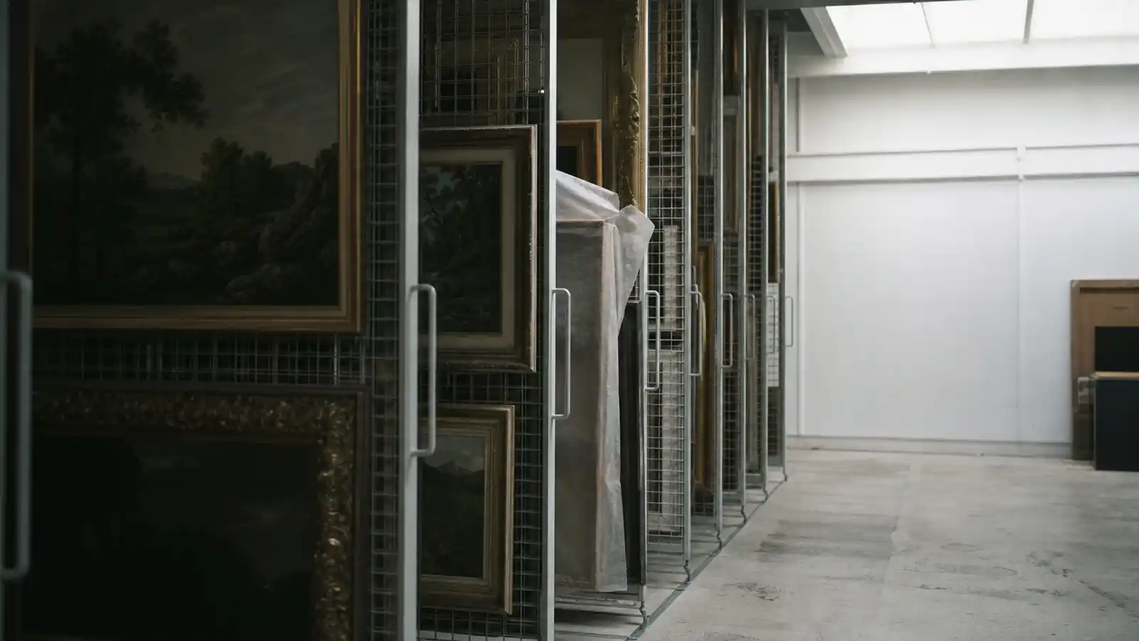 Paintings stacked on gallery storeroom racks, art valuer professional indemnity insurance