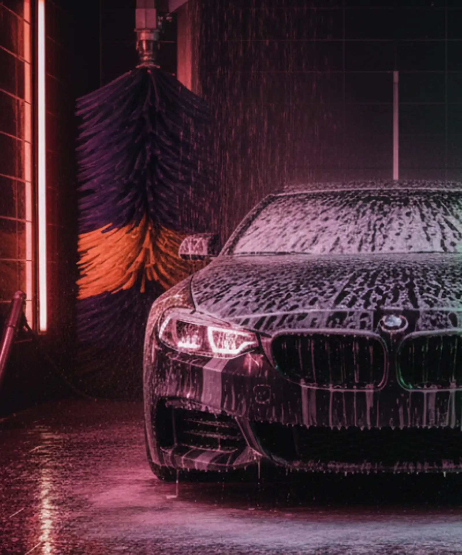 Rear view of a sedan in an automatic car wash bay being sprayed with water and foam, representing operational risks and business insurance for car wash owners.