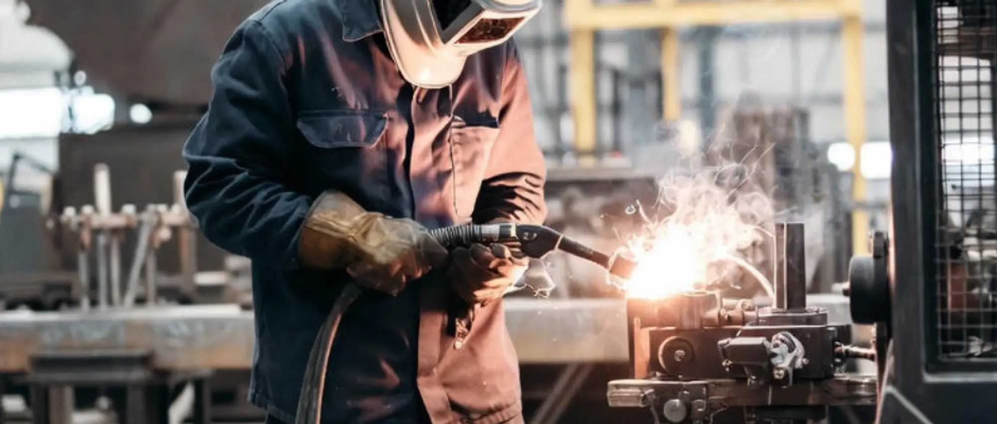 Close-up of a welder in a workshop focusing on a pipe joint, representing public liability and professional indemnity insurance for Australian metalworkers.