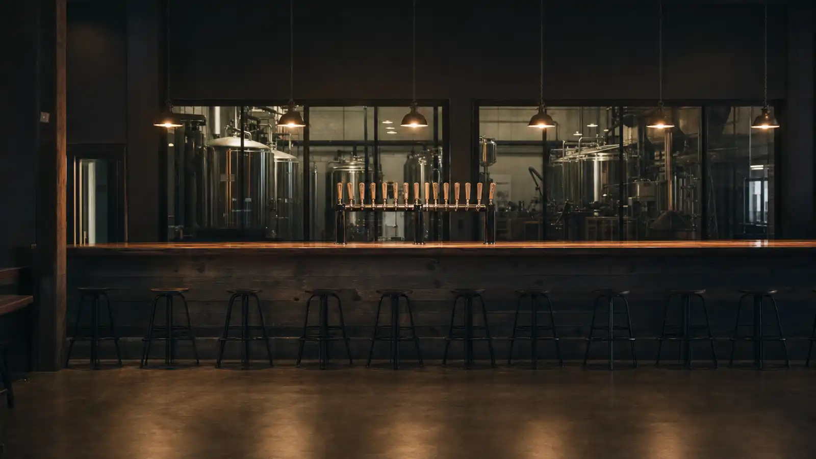 Brewery taproom at dusk with fermentation tanks behind the bar, brewery tour insurance in Australia