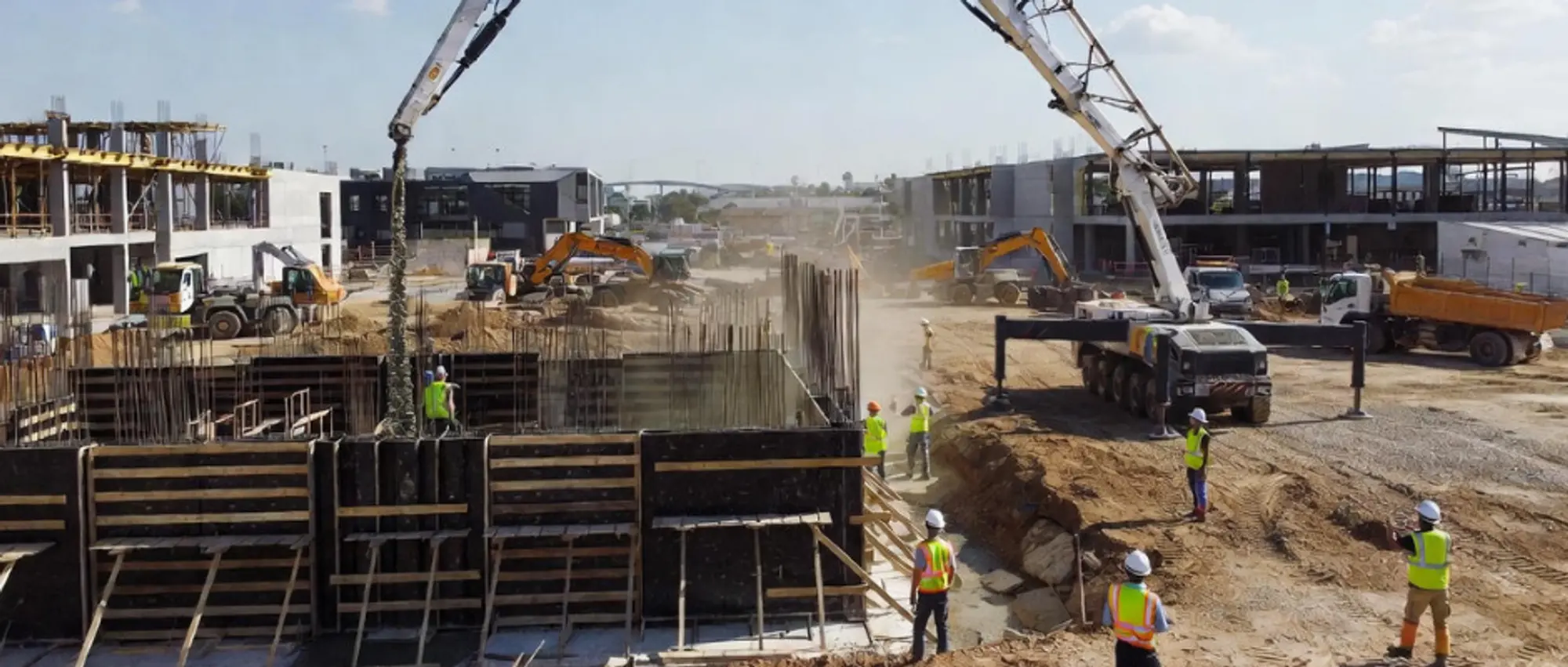 Concrete pump truck with extended boom arm on commercial construction site demonstrating liability protection needs for pumping contractors