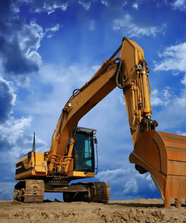 Large tracked excavator with raised bucket against blue sky for heavy earthmoving machinery insurance