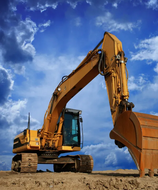 Large tracked excavator with raised bucket against blue sky for heavy earthmoving machinery insurance