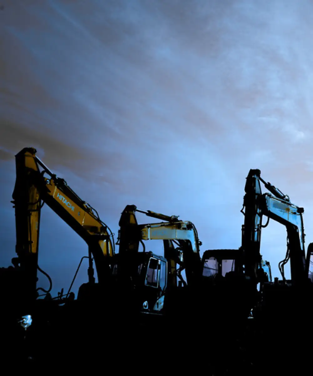 Fleet of excavators silhouetted against twilight sky for earthmoving equipment insurance and plant cover