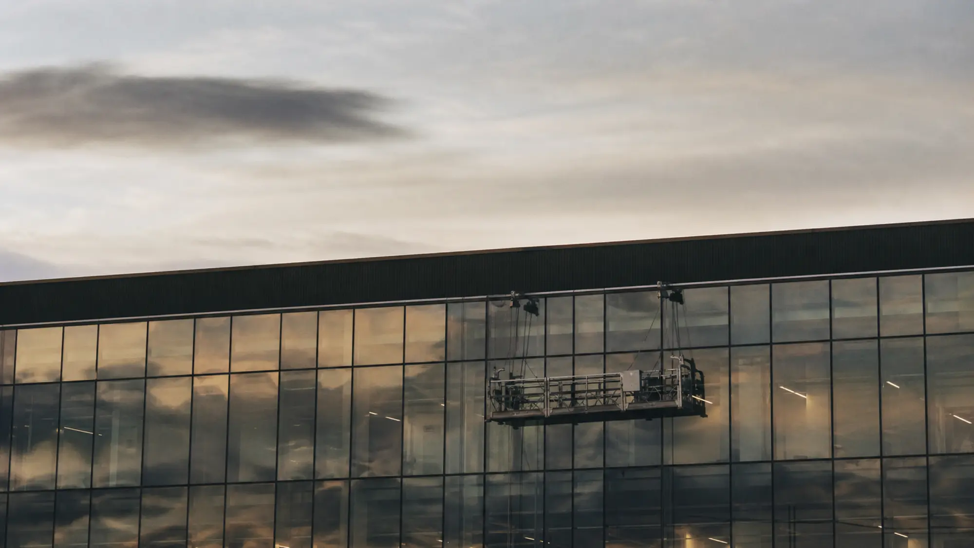 Glass facade with access platform at dusk - insurance for facade engineering consultants
