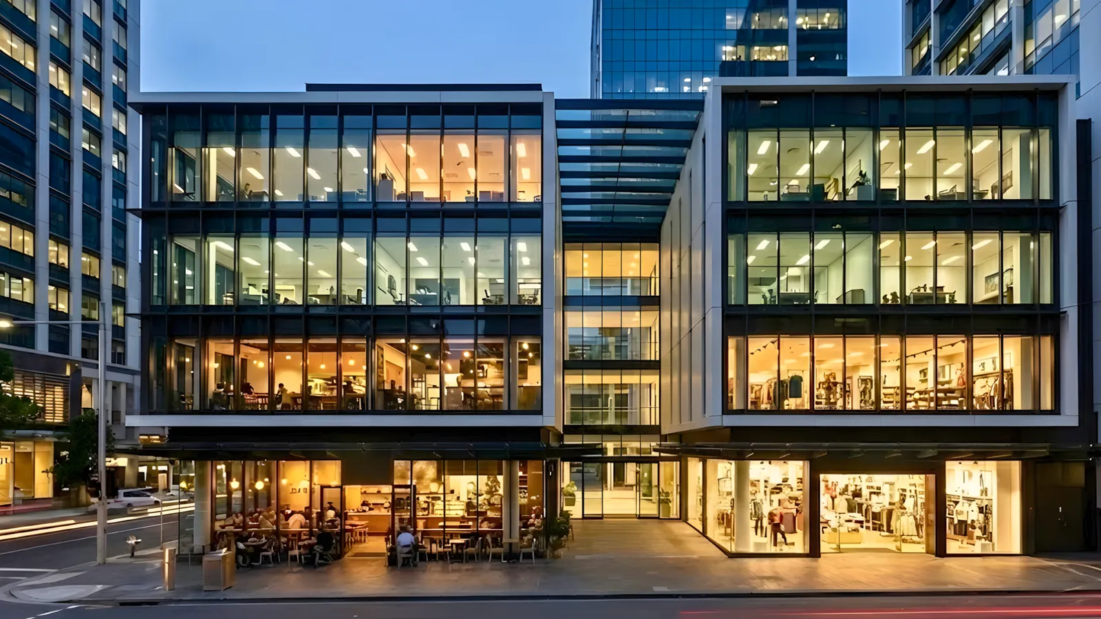 Illuminated modern mixed-use commercial building featuring retail shops and office spaces at twilight.