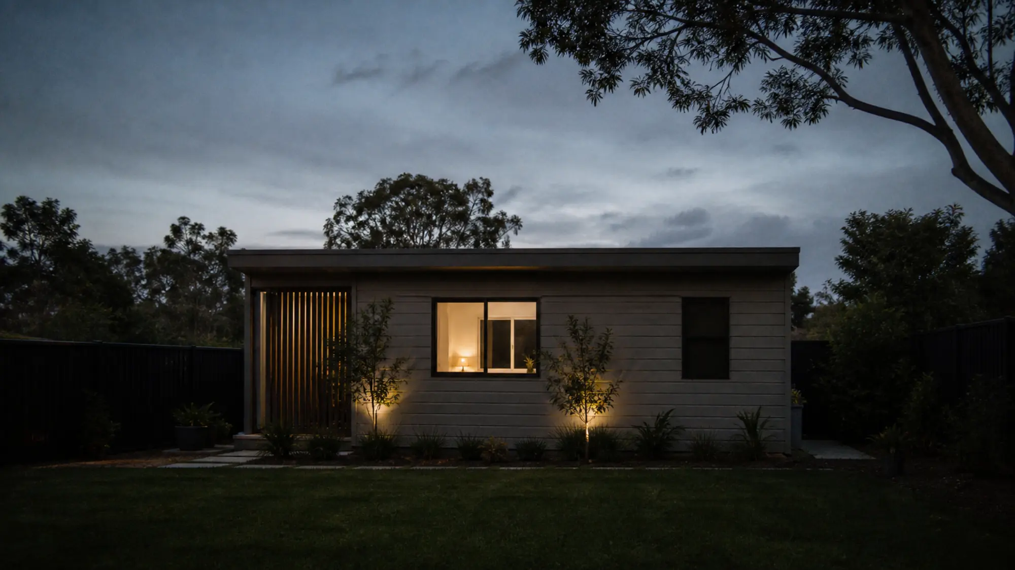 Dual occupancy dwelling exterior at dusk with warm interior lighting for landlord insurance