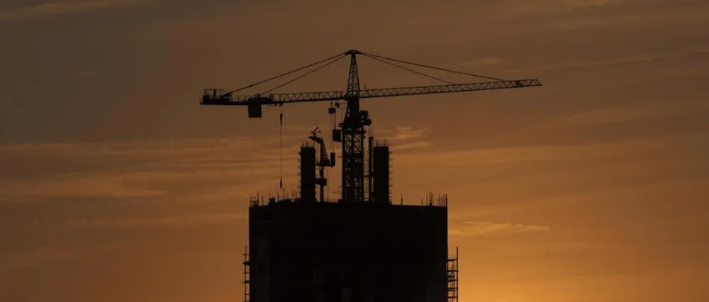 Tower crane silhouette on high-rise construction site at sunset