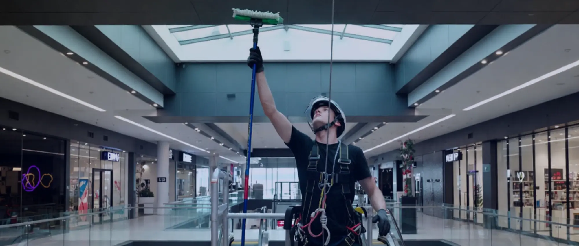 Window cleaner in safety harness cleaning shopping centre skylight – illustrating high-risk commercial cleaning operations requiring specialist public liability insurance