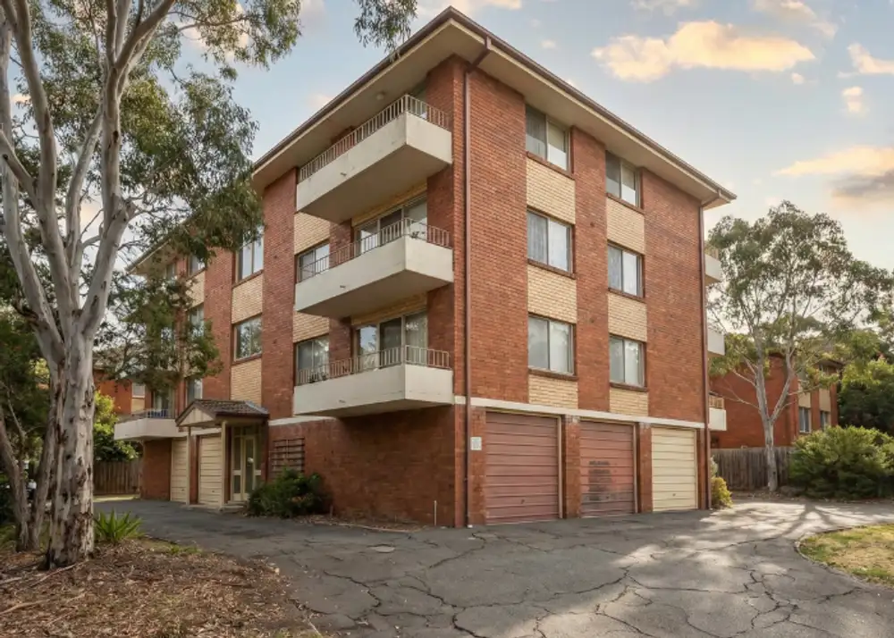 A four-story brick apartment building with white balconies and garages, insured under a non-strata policy.