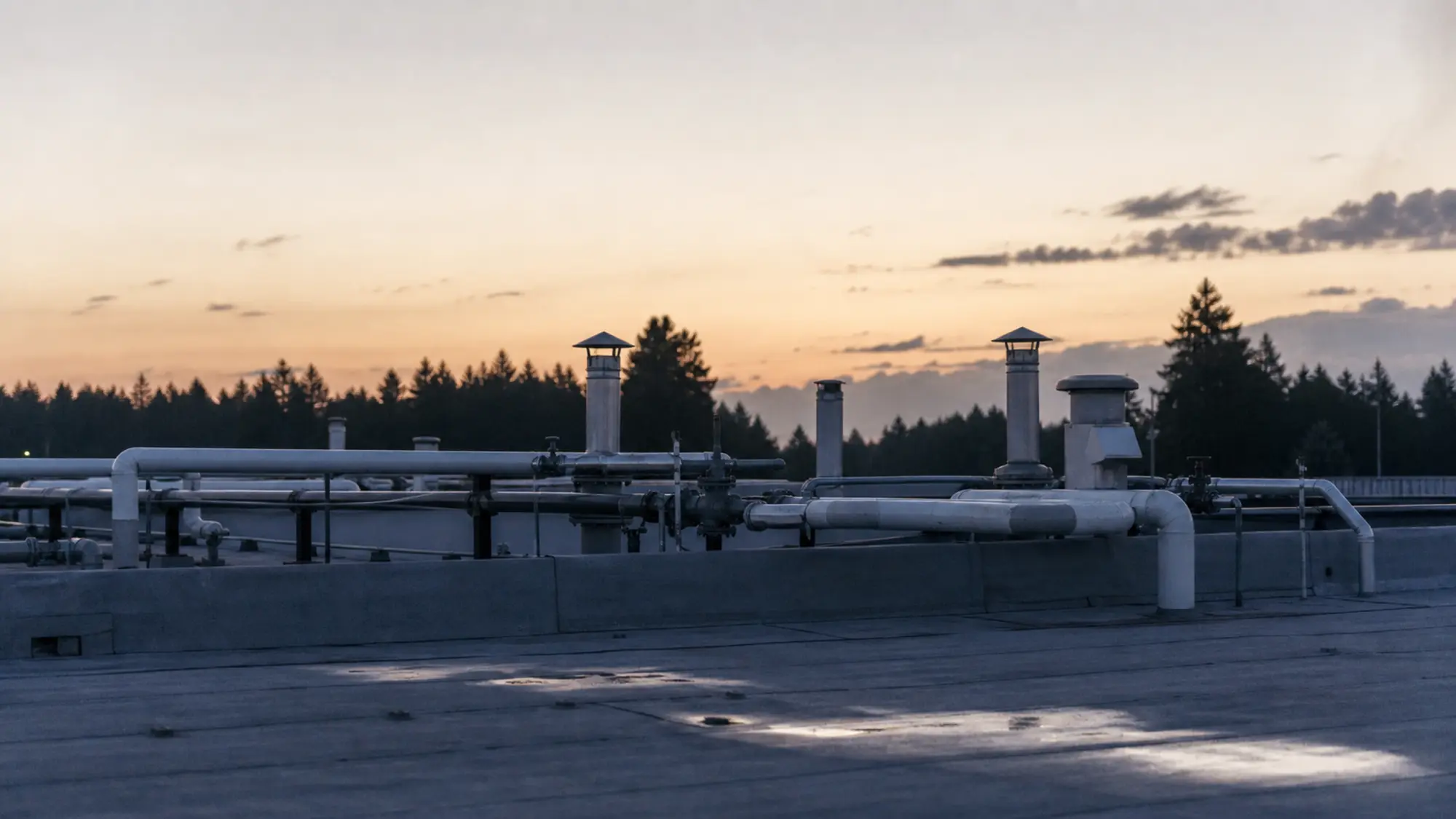 Rooftop hydraulic pipework at dusk - get a plumbing engineer insurance quote