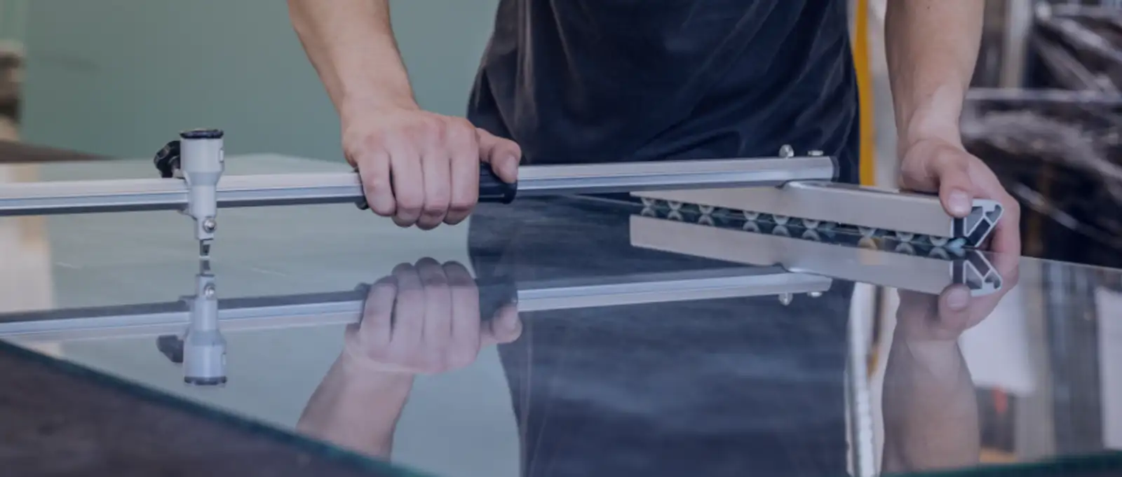 Glazier using professional glass cutting tool with suction cups to score and cut large glass panel to AS1288 specifications