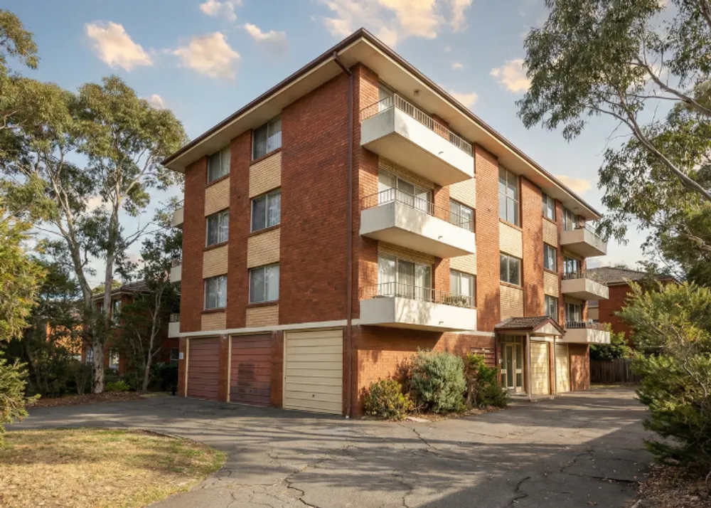 A classic three-story brick block of units with integrated garages, demonstrating the type of asset covered by non-strata building insurance.