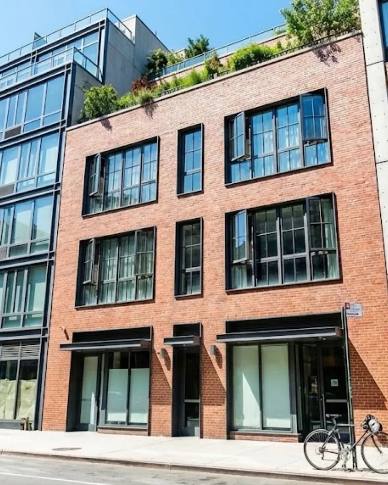 Modern brick apartment building with ground-floor commercial space and large architectural windows in an urban setting.